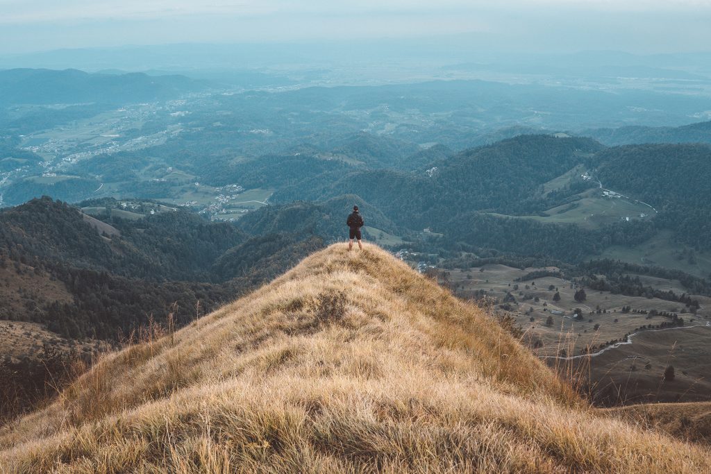 Kamniski vrh, Slovenia - September 2018: A man (photographer) standing at the end of a hill looking at Kamnik.